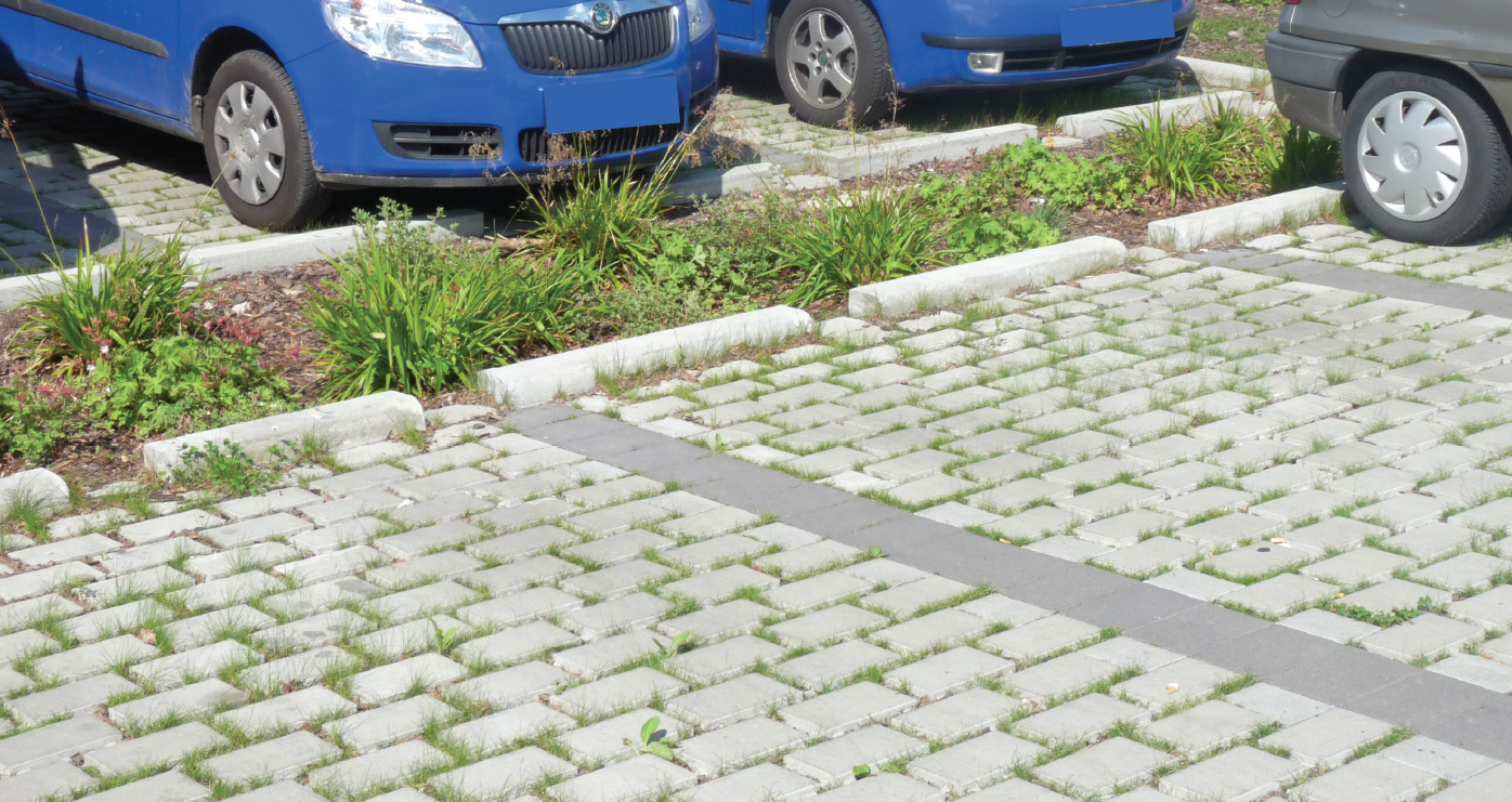 Parkplatz mit Autos, Straßenbeet und durchlässige Pflastersteine
