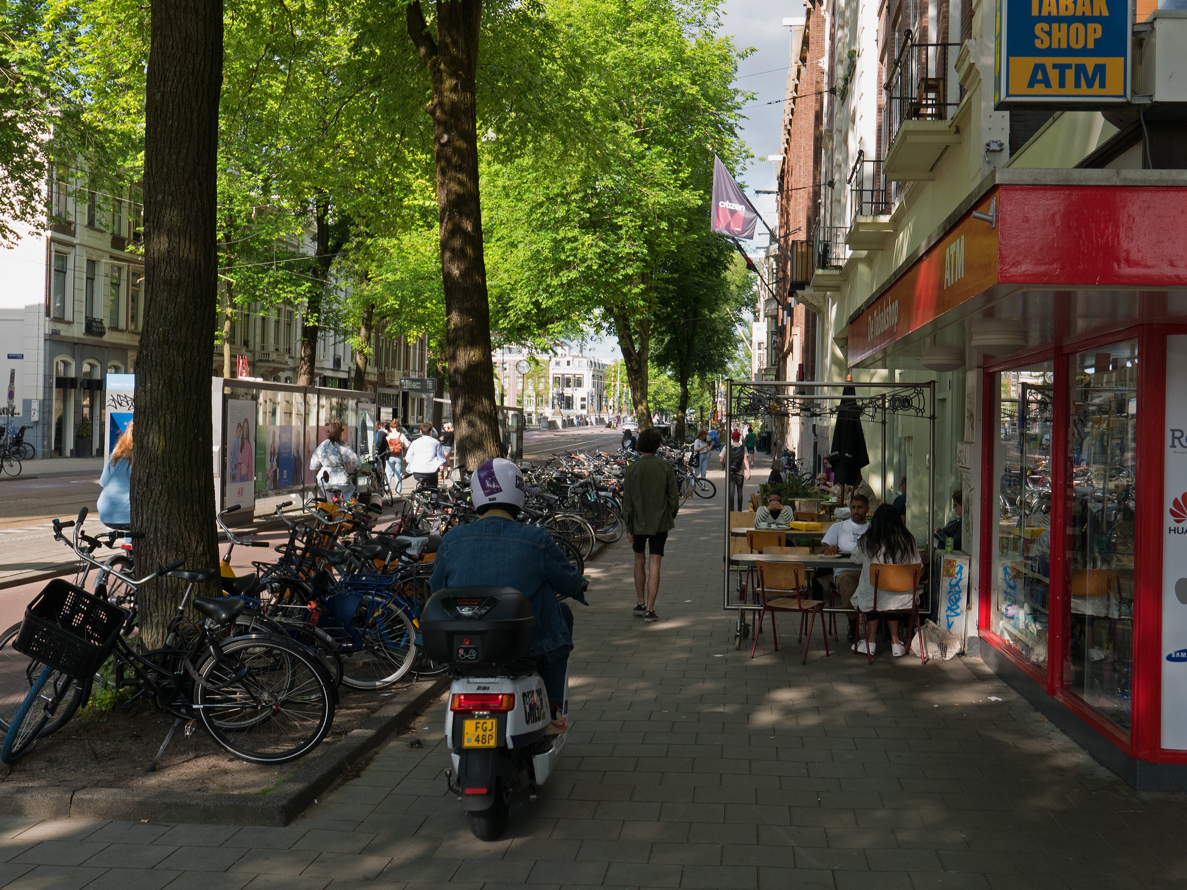 belebte Straße mit Menschen und Bäumen in Baumscheiben