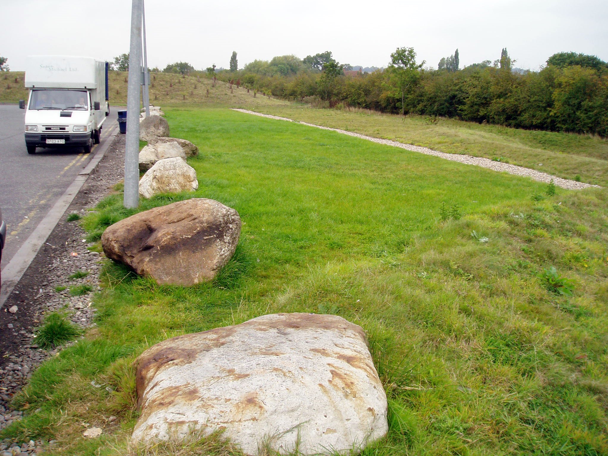 grüner Filterstreifen am Rande einer befahrenen Straße. 