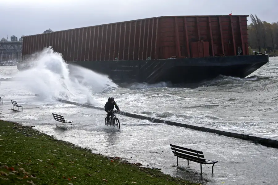 Ein Radfahrer fährt auf einem überschwemmten Weg, ein Schiff macht Wellen welche sich bis auf den Weg ausbreiten.